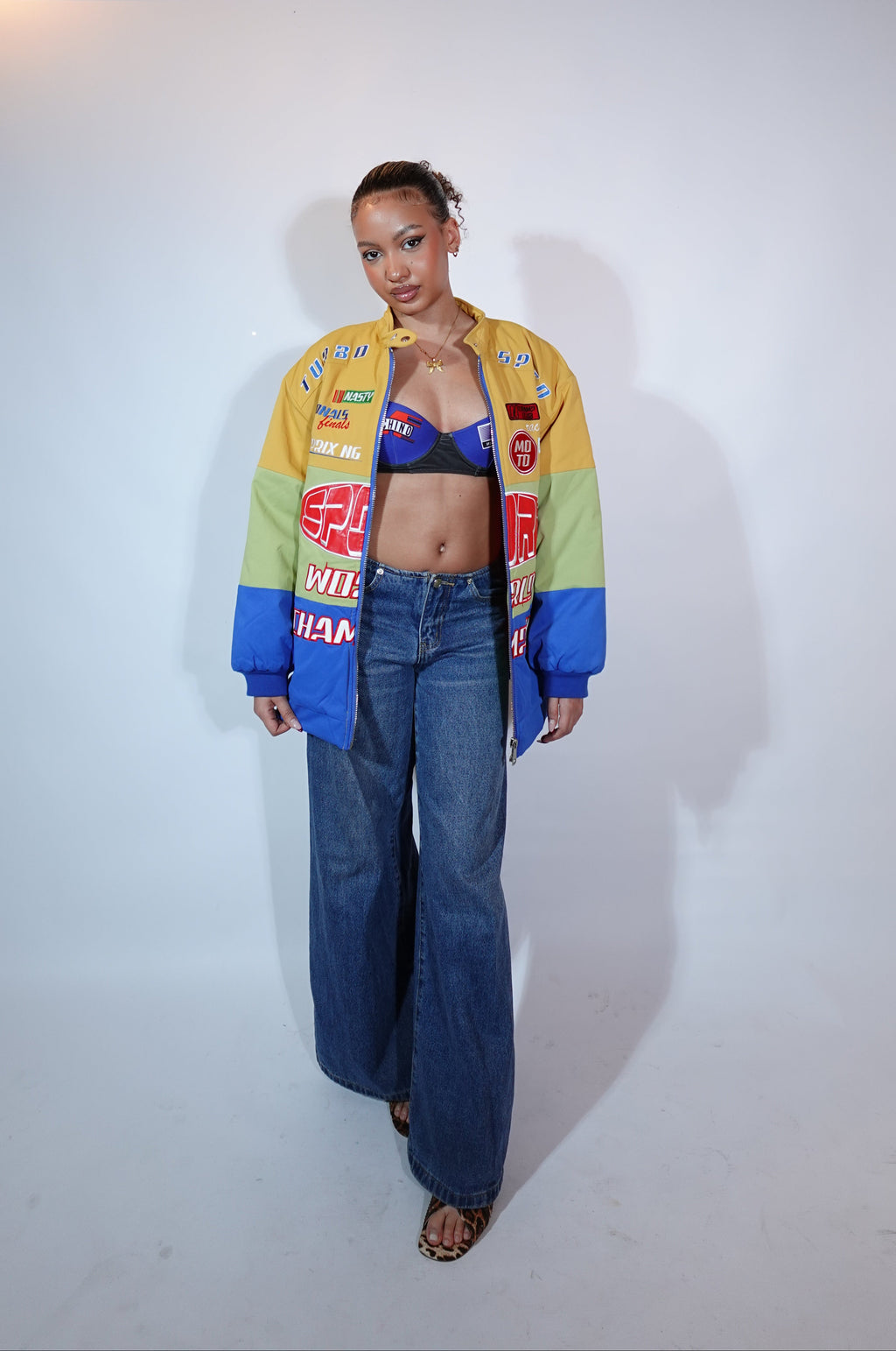 Person wearing a colorful jacket and blue jeans on a white background