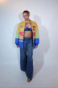 Person wearing a colorful jacket and blue jeans on a white background